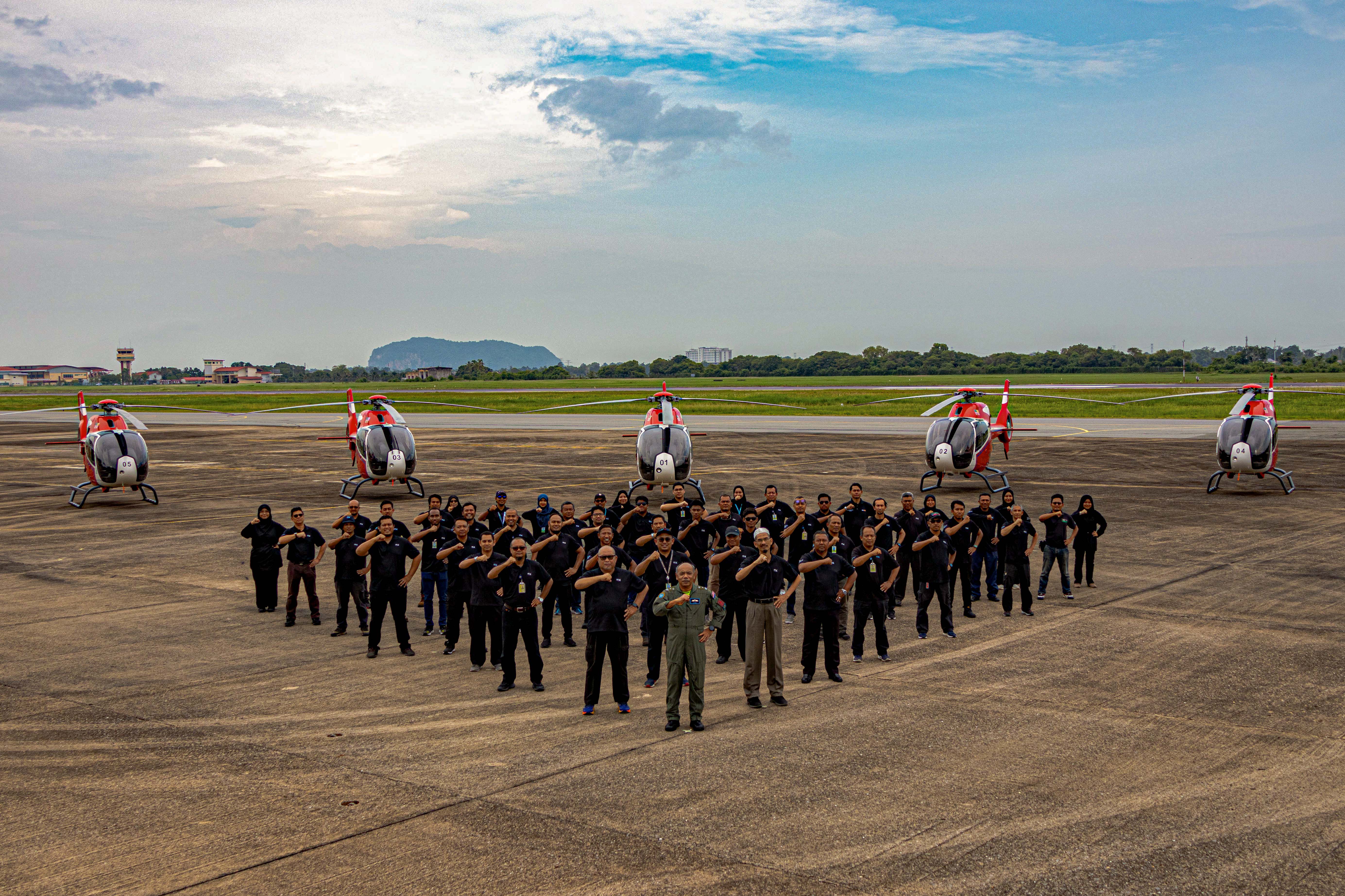 GKSB team standing in formation with five H120 helicopters on the flight line